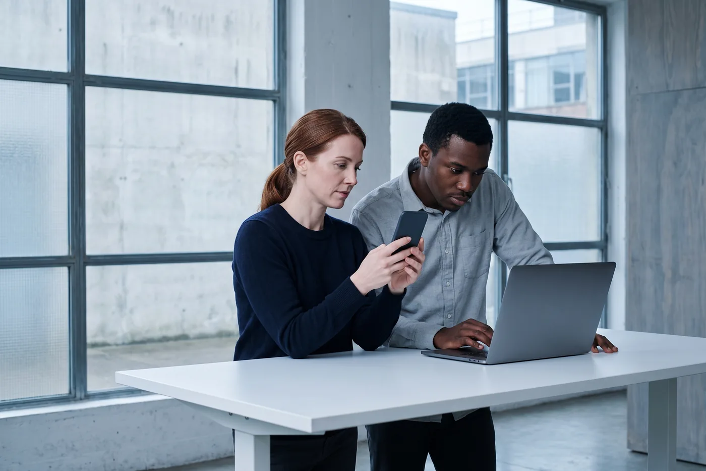 Two product designers checking a release on a phone and a laptop